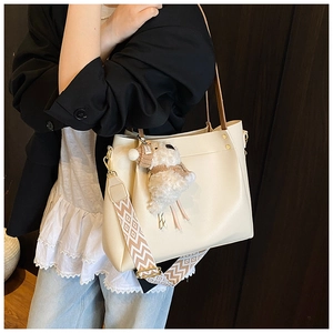 Detail view of beige tote bag with wide jacquard strap and plush sheep pendant charm