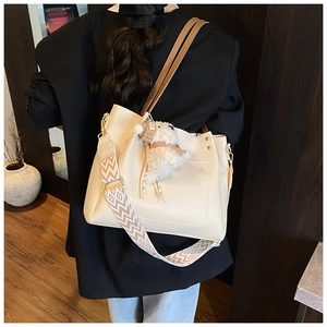 Off-white tote bag with geometric strap and cute lamb pendant shown from the side