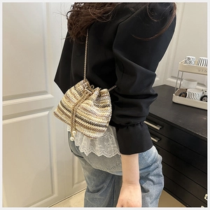 Détail du sac seau tissé avec rayures, chaîne métallique et breloques en perles blanches