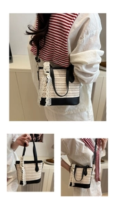 Detail of woven straw tote with black leather trim and lace ribbon in indoor setting