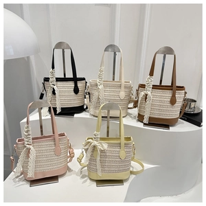 Five assorted colors of woven straw bucket bags with lace bows and detachable straps