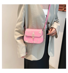Detail of pink crossbody bag with floral lace embroidery and golden twist lock closure