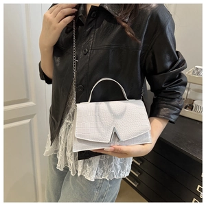 White crocodile pattern crossbody bag with silver V-buckle worn by a model