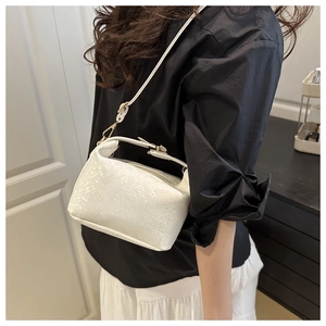 Detail of white snake-embossed mini pillow bag with gold hardware and slim strap