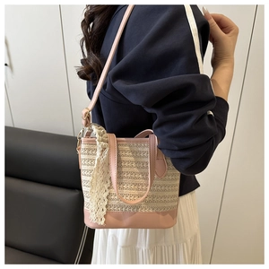 Close-up of woven straw bucket bag with pink leather trim and elegant lace detailing