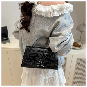 Detailed view of black crocodile pattern faux leather handbag with silver chain and A-shaped clasp