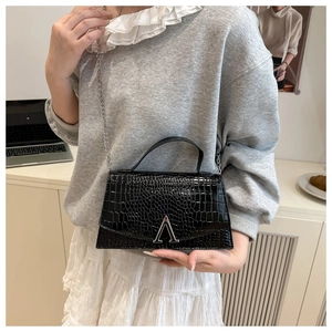 Close-up of black crocodile embossed small square bag with silver A-shaped metal clasp