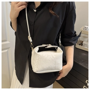 Close-up of white mini crossbody bag with snake-skin texture and gold hardware on a model
