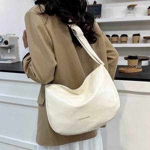 Minimalist cream white crescent hobo bag for women with adjustable strap shown outdoors