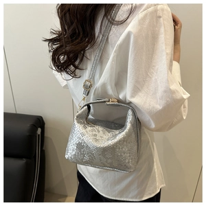 Detail of silver snake-embossed mini crossbody bag showing metallic texture and scale pattern