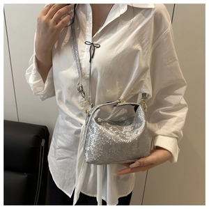 Detail of silver snake-patterned pillow bag worn with a white shirt and black bottoms