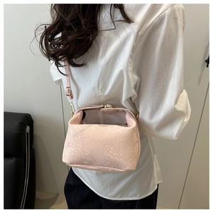 Detail of pink snakeskin pattern crossbody bag with golden metal clasp and strap