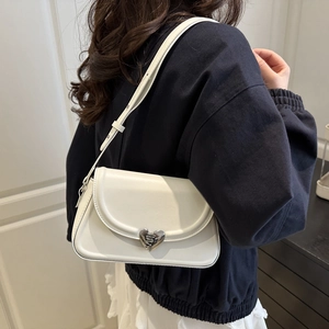 French style white leather shoulder bag with silver heart buckle worn by model