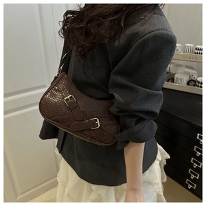 Detail of dark brown faux crocodile leather shoulder bag with gold buckle straps