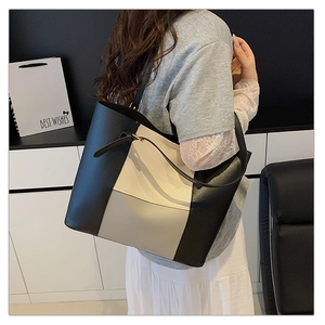 Close-up of a large black and white contrast tote bag worn by a model in a minimalist room