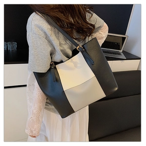 Detail of a large black and white contrast leather tote bag carried over the shoulder
