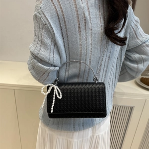 Chic black woven leather handbag with silver handle and pearl bow charm detail