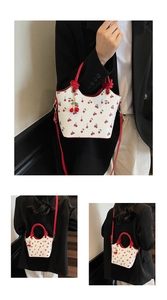 Détail du mini sac seau blanc à imprimé cerises avec pendentif décoratif