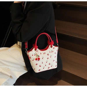 Détail du sac bandoulière à imprimé cerise avec un joli charm de cerise rouge