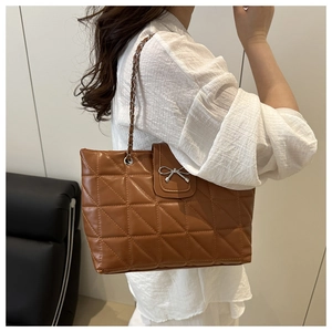 Gros plan du sac cabas matelassé marron avec boucle en forme de nœud argenté
