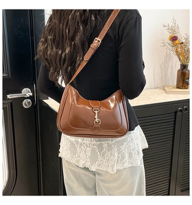 Detailed close-up of brown glossy crescent bag with golden piston metal closure