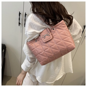 Detail showing pink quilted tote with metal bow buckle and chain strap on a model