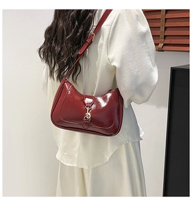 Détail du sac sous l'aisselle en cuir brillant rouge foncé avec fermoir doré élégant