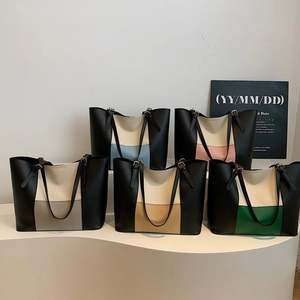 Five minimalist color-block PU leather tote bags displayed on a modern white pedestal