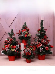 Detailed close-up of mini Christmas trees with pine cones, red berries and plaid ribbons