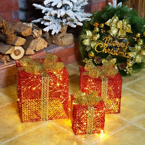 Three-piece red metal Christmas gift boxes with gold bows and warm LED lights
