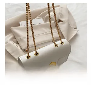 Detailed view of white crossbody bag featuring unique eyelet design and gold chain strap