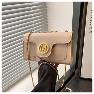 Detailed close-up of beige leather crossbody bag with golden M logo and chain strap