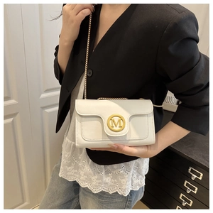 Detailed view of the gold 'M' buckle and delicate chain strap on a white leather bag