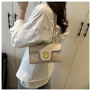 Detail of elegant beige quilted crossbody bag with gold M-logo buckle and chain strap