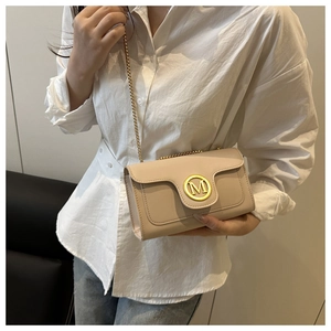 Detail of beige quilted crossbody bag featuring gold chain strap and M-logo metal buckle