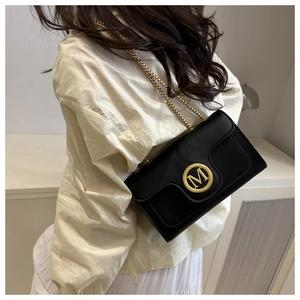 Detail of crossbody bag featuring gold M logo emblem and elegant chain shoulder strap