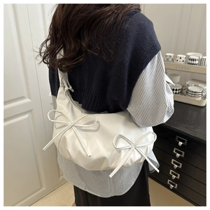 Detail of white pleated hobo bag with cute bow accents and glossy leather finish