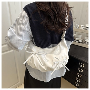 Detail of white pleated crescent shoulder bag with two bows on smooth faux leather