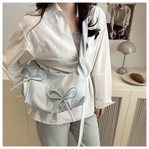 Détail du sac bandoulière croissant bleu clair avec deux nœuds décoratifs élégants