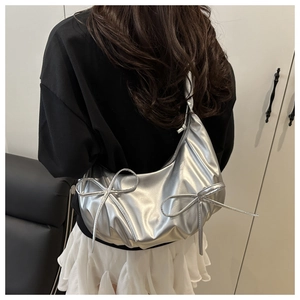 Detail of silver metallic hobo bag with bow ornaments and textured synthetic leather
