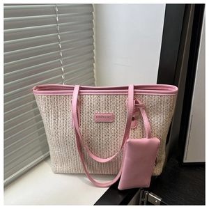 Detail of woven straw tote bag featuring pink leather trim and a matching mini pouch