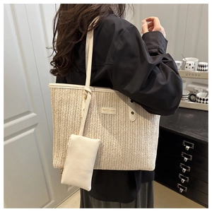 Detail of woven tote bag featuring white leather handles and a matching zipper pouch
