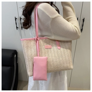 Detail of pink faux leather trim and fashion logo on a beige straw woven tote bag