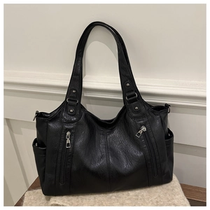 Close-up detail of black tote bag showing leather texture and vertical zipper pockets