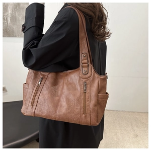 Detail view of a vintage brown leather tote bag with dual decorative metal zippers