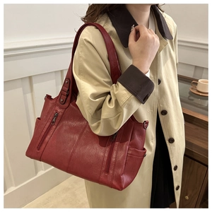 Side view of large red tote bag with multiple zipper pockets on female model