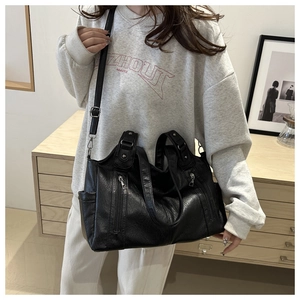 Détail du sac cabas noir avec fermetures éclair argentées porté par un mannequin