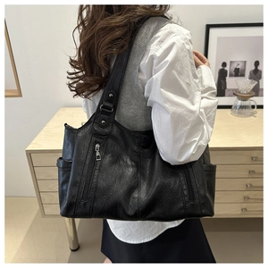 Detail of black leather tote bag with vertical zipper pockets on a stylish model