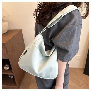 Detail of mint green crossbody bag showing side label and adjustable wide shoulder strap