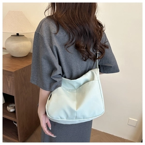 Detail of light green canvas bucket bag showing front pocket and textured fabric finish